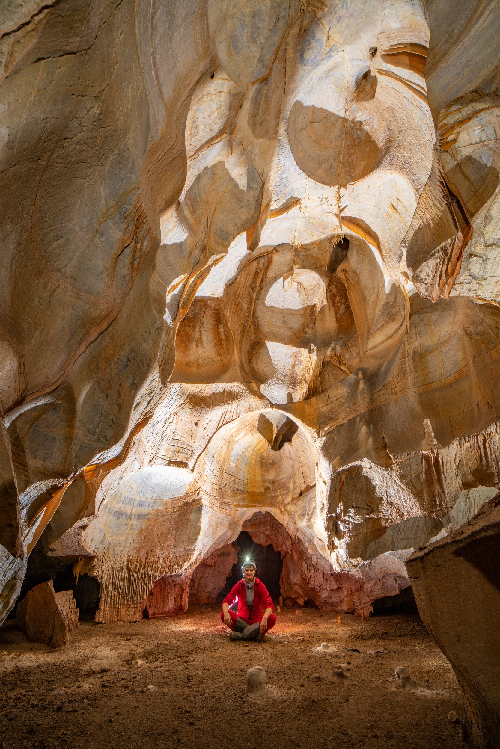 Caver among pale rounded rock formations inside Melisotripa Cave